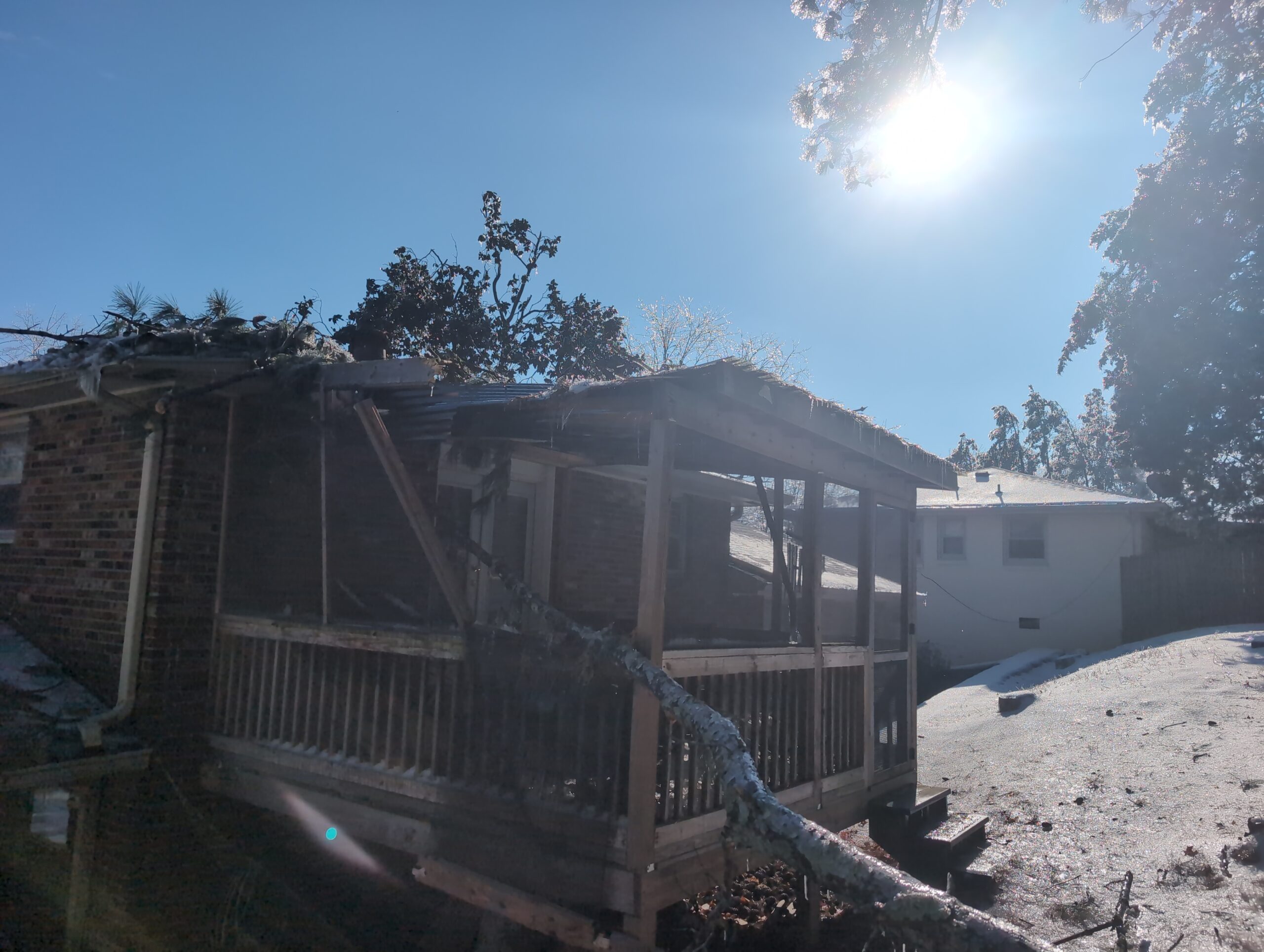 This image shows a screened in porch that was damaged by a falling tree.
